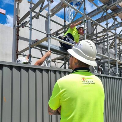 man in hard-hat and high vis shirt overlooking Scaffolding on a worksite